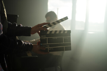 Clapperboard or clipboard in hands. Guy is directing and filming retro cinema or vintage movie. Composer man play on the old piano.