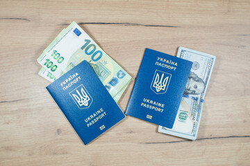 Ukrainian biometric passports id to travel the Europe with dollars and euros money on the table. Inscription in Ukrainian "Ukraine Passport". Travel or migrants concept.