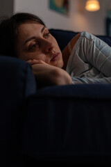 Fototapeta na wymiar Caucasian woman with chronic depression feeling sad in living room, dealing with mental health disease and illness. Depressed anxious person in despair laying on couch. Close up.
