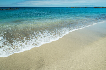 Fototapeta na wymiar Ocean foam covering beautiful long sandy beach.