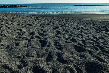 Ocean foam covering wonderful black sand beach of Tenerife island.