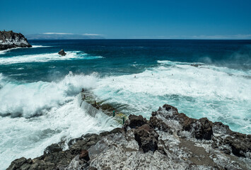 Obraz premium Rocky coastline and big wave breaking on natural swimming pool of Tenerife Island.