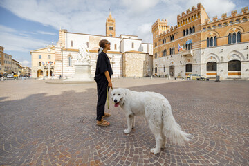 Woman with dog walking in Grosseto town the center of Maremma region in Italy. Maremmano abruzzese...