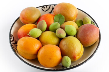 Naklejka na ściany i meble green fresh apricots and ripe apricots in the plate