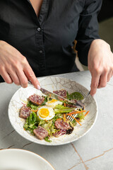 salad with tuna, lettuce, herbs, egg, on a gray table
