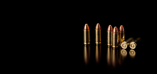 Pistol cartridges 9 mm on a smooth glossy surface with reflections. Ammunition for pistols and PCC carbines on a dark back.