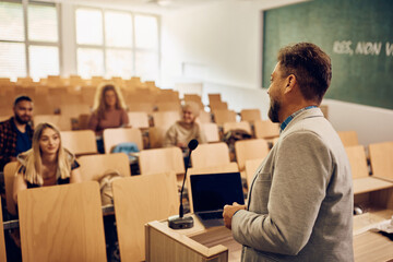 Fototapeta premium Male professor teaching group of students during class at college classroom.
