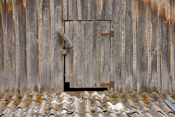 closed wooden door to an attic in rustic wooden house with slate roof under