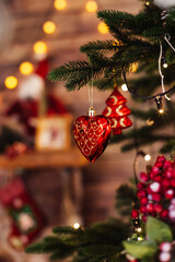 A Christmas toy is hanging on a branch of a fir tree against the background of garland lights.