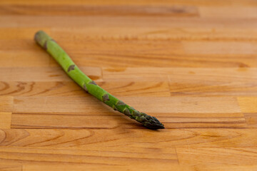 a single spear of green asparagus on a wooden background
