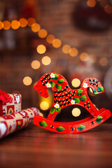A wooden red horse on the background of a Christmas garland.