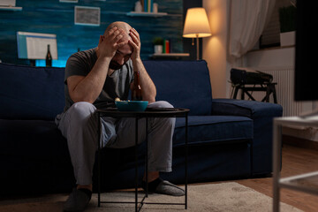 Frustrated man watching sports on television program and feeling sad about football team losing...