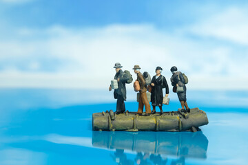 Miniature people toy figure photography. A group of refugees riding the raft escape from conflict area to save place because of war. - obrazy, fototapety, plakaty
