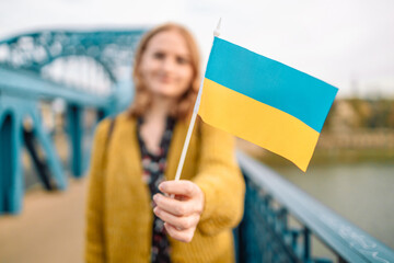 Caucasian hands hold Ukraine nation flag on wall background.People protest against the war in...