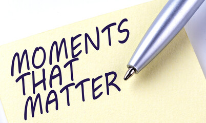 Sticky Note Message MOMENTS THAT MATTER with pen on the white background