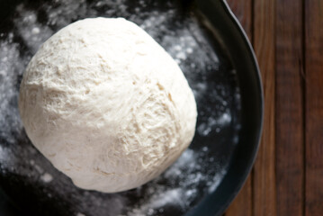 Fototapeta na wymiar yeast dough for bread or pizza on a floured surface, with flour splash. Cooking bread.