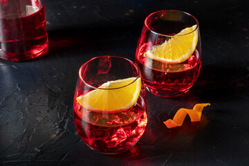 Negroni aperitif cocktail with aperol, campari and fresh oranges, a cold drink, on a black...