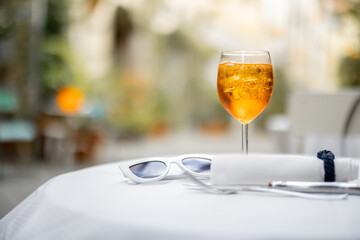 Spritz Aperol drink on a table with sunglasses at restaurant on cozy street outdoors. Concept of...