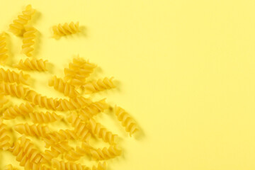 Pasta fusilli on yellow background, flat lay, top view with copy space	