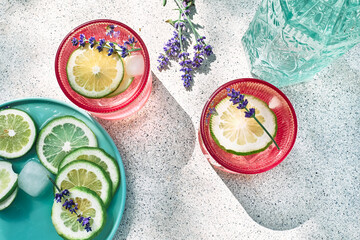 Cool lavender lemonade with lime slices and lavender flower on the table near pastel light blue background. Healthy organic summer soda drink. Detox water. Diet unalcolic coctail.