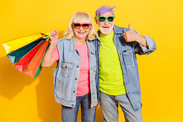 Photo of excited confident husband wife wear jeans shirts having shopping thumb up isolated yellow color background