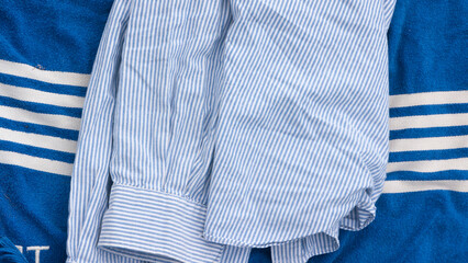Camisa de rayas azul y blanca sobre toalla azul con rayas blancas
