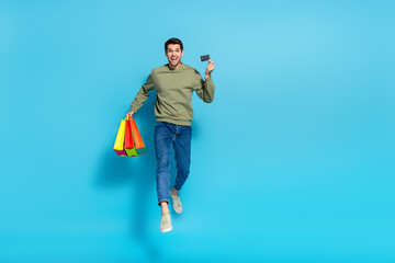 Full length photo of active energetic guy hold debit card mall packages isolated on blue color...