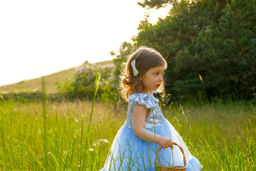 child walks in the park. little girl dressed in a blue dress.