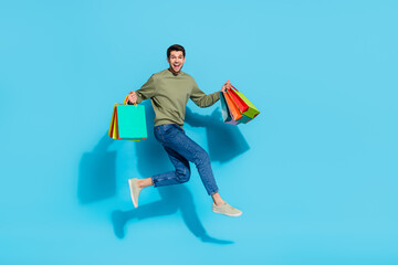 Full size photo of crazy handsome guy hurry rush hold packages jump isolated on blue color...