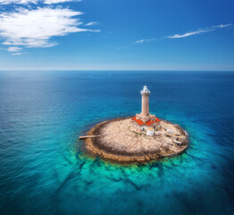Lighthouse on smal island in the sea at sunny day in summer. Aerial top view of beautiful...