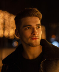 Stylish dark portrait of a fashion handsome young guy model with hair in a fancy leather jacket in...