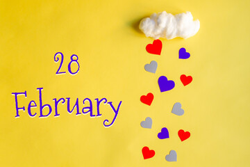28 february day of month, colorful hearts rain from a white cotton cloud on a yellow background....