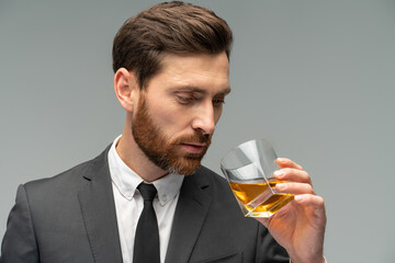 Waist up portrait view of the attractive handsome smells whiskey from the glass in his hands.Stylish and successful men concept
