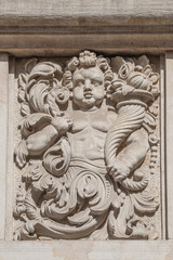 Old relief bar of a small child with Cornucopia, horn of plenty in the historical downtown of Dresden, Germany, details, closeup.