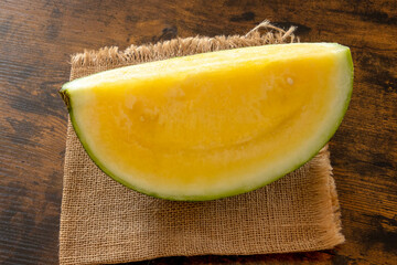 slice of fresh ripe yellow watermelon on the wooden background