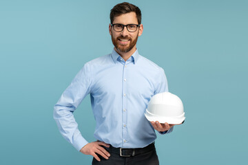 Young architect man with happy face holding builder safety helmet and smiling while looking at the...