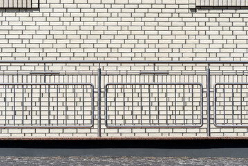 Background of the facade of the building made of white brick, visible metal railing.