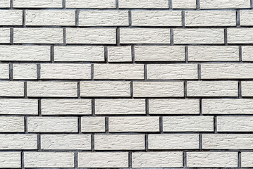 Background made of the facade of the building made white brick, a large fugue between the bricks is visible.