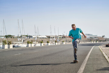 young man riding a skateboard on a road next to the port in the morning