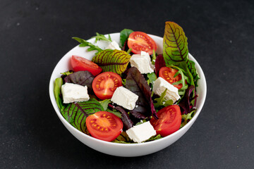 Caesar salad on black plate isolated on white