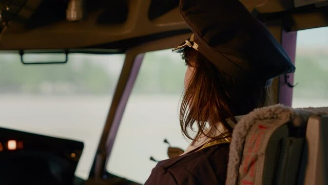 Portrait of female copilot in aviation uniform flying airplane from cockpit command, using power engine and navigation on dashboard. Control panel buttons to fly aircraft and takeoff.