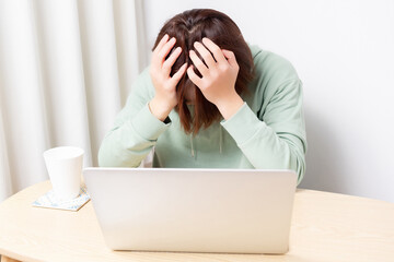 パソコンを使いながら落ち込んでいる女性