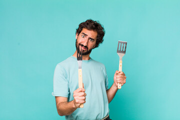 young adult hispanic crazy man with barbecue tools