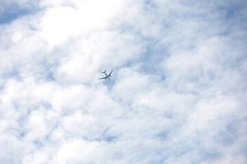 Airplane flying in the blue sky covered with white clouds. Passenger plane at flight, travel concept