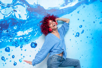 portrait of a happy smiling young latin woman with red afro hair having a good time dancing and...