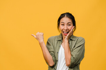 Portrait of young Asian lady smiling with cheerful expression, shows something amazing at blank...