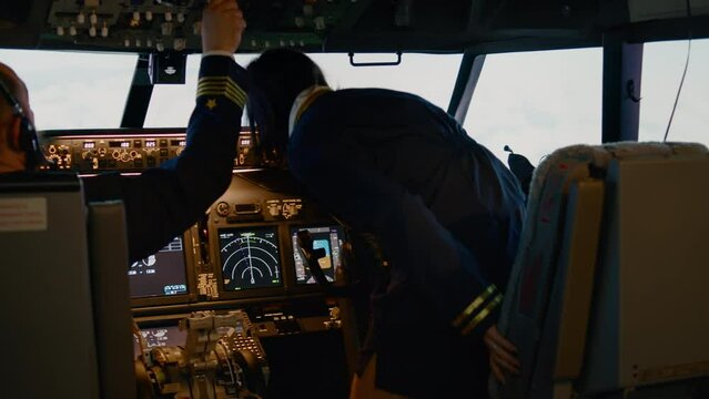Team of captain and woman copilot fixing altitude and longitude to fly airplane with control panel dashboard in cockpit. Throttling engine and taking off with navigation compass. Handheld shot.