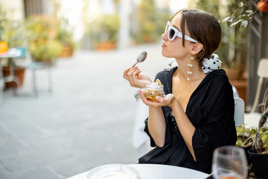 Fototapeta Woman eating tiramisu dessert at the restaurant outdoors. Concept of italian cuisine