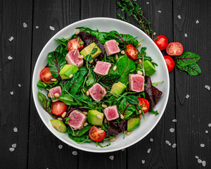 Japanese traditional salad with pieces of medium-rare grilled Ahi tuna and sesame with fresh vegetable on a bowl.