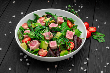 Japanese traditional salad with pieces of medium-rare grilled Ahi tuna and sesame with fresh vegetable on a bowl.